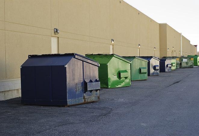 a construction worker empties a wheelbarrow of waste into the dumpster in Augusta